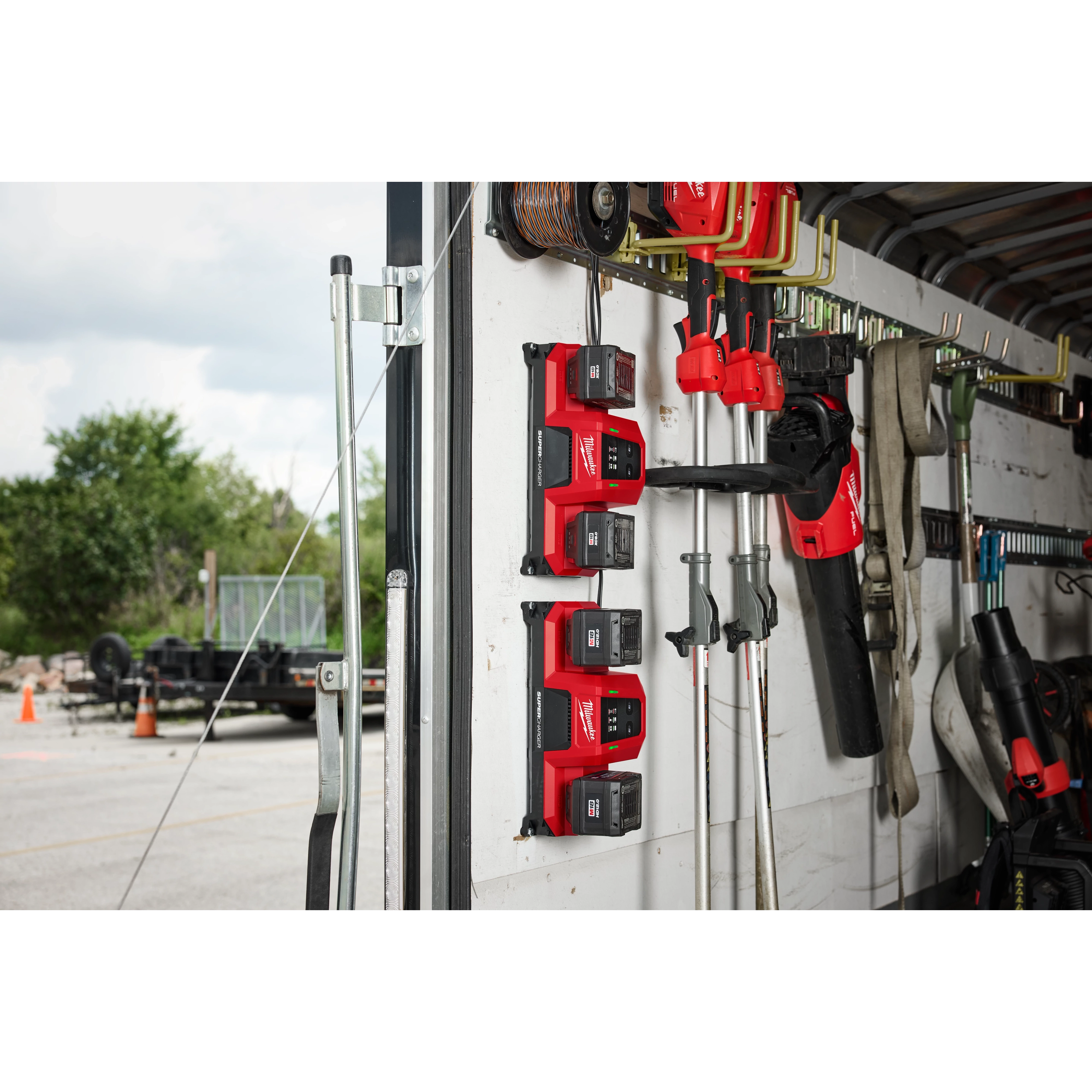 Various power tools and garden tools are neatly organized on a wall-mounted rack inside a garage or workshop.