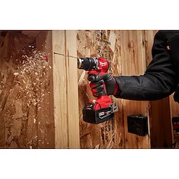 Worker using the Compact Brushless Hammer Drill/Driver to drill out a hole through studs