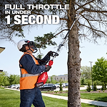 A person wearing safety gear uses an M18 FUEL™ Pole Saw w/ QUIK-LOK™ Kit to trim branches on a tree. The individual is standing on the ground and extending the pole saw to reach high branches. Text on the image reads, "FULL THROTTLE IN UNDER 1 SECOND." The background features a grassy area with trees, a sidewalk, and parked cars.