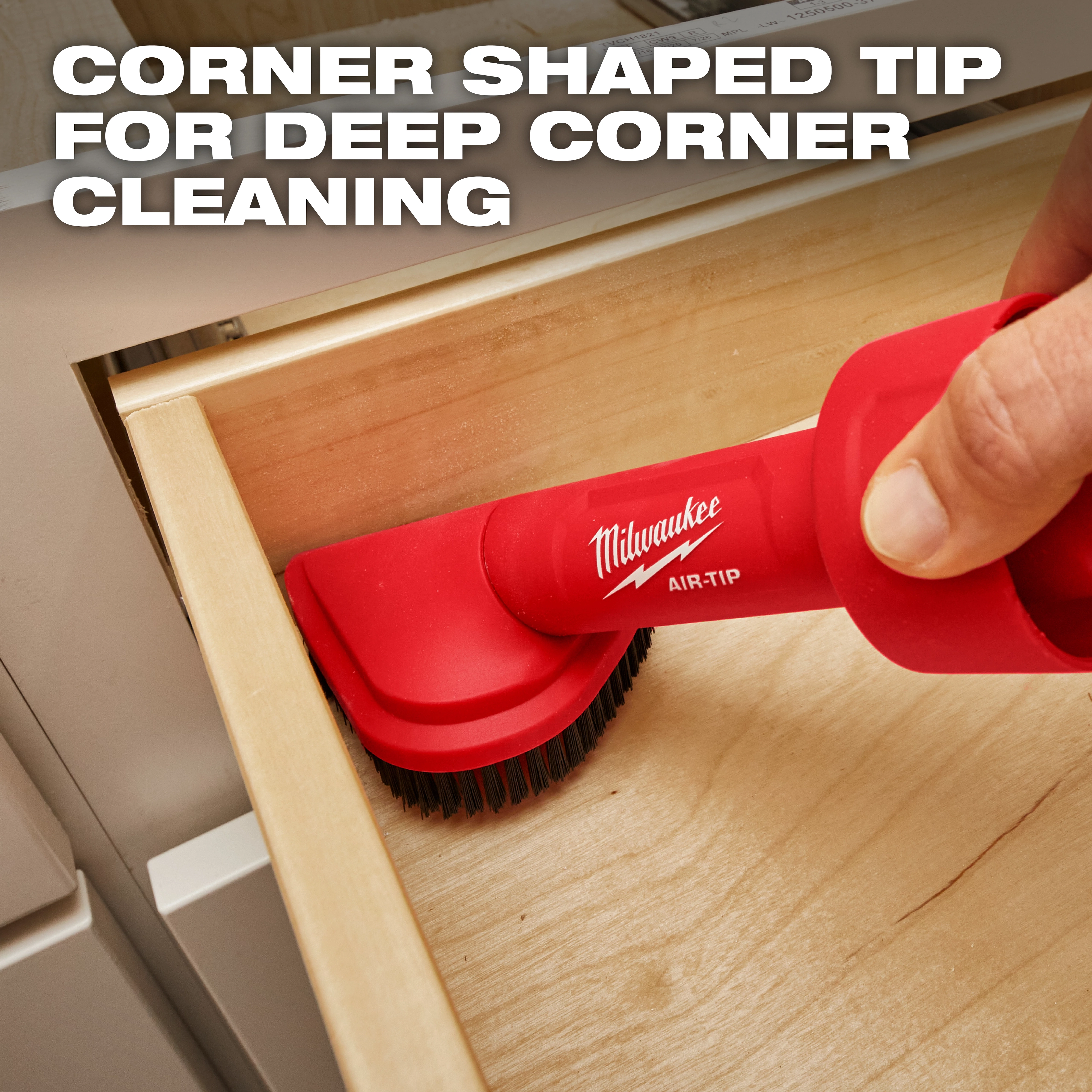 A person uses the red AIR-TIP™ Rotating Corner Brush Tool to clean the corner of a wooden drawer. The brush head is shaped to fit into corners. Text overlay reads "Corner Shaped Tip for Deep Corner Cleaning."