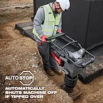 A construction worker operates the MX FUEL™ 70 kg Rammer, standing on a sandy site. Text overlay states, "AUTO STOP: Automatically shuts machine off if tipped over." The worker is wearing safety gear, including a vest and gloves.