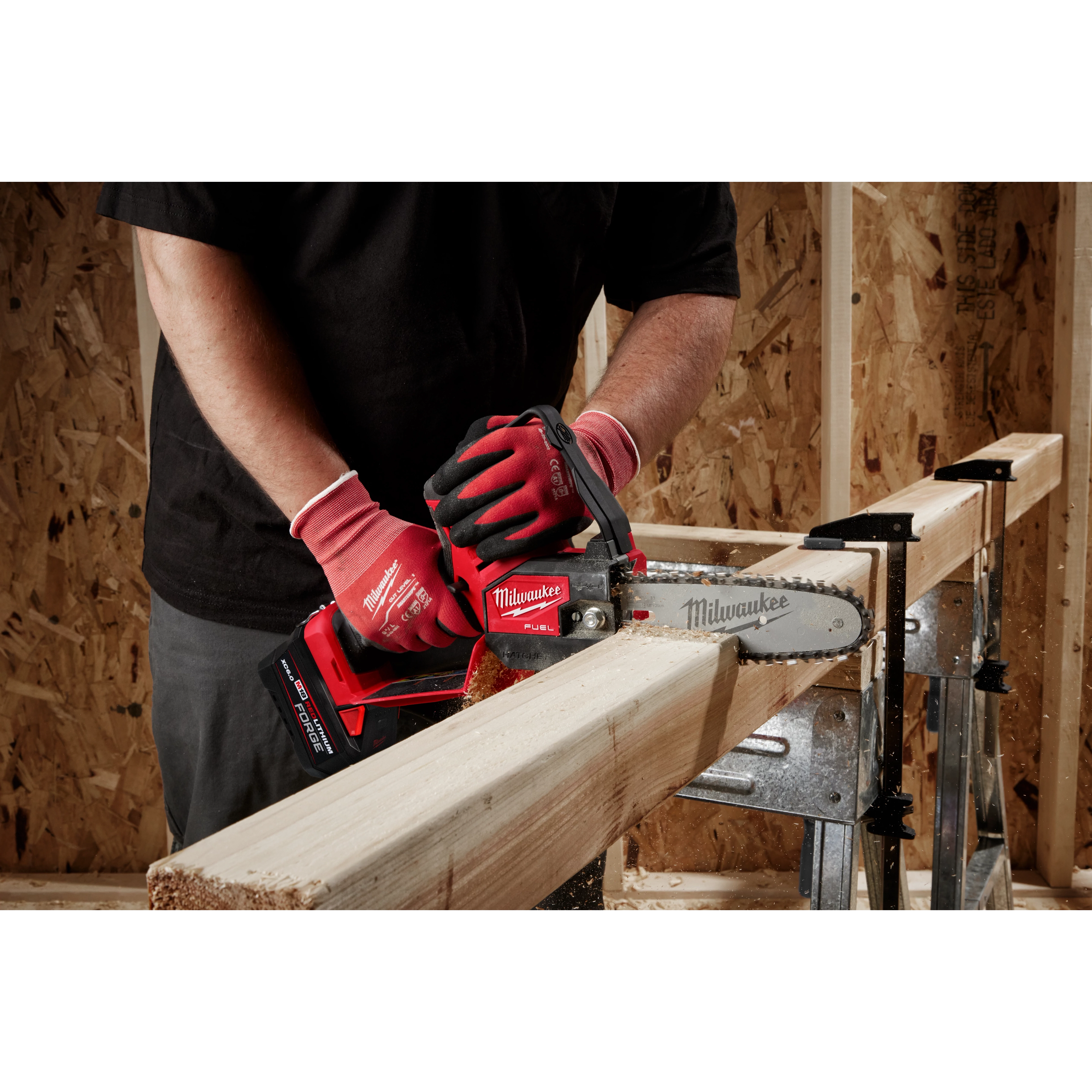 A person using a red Milwaukee chainsaw to cut a wooden beam supported by a sawbuck.