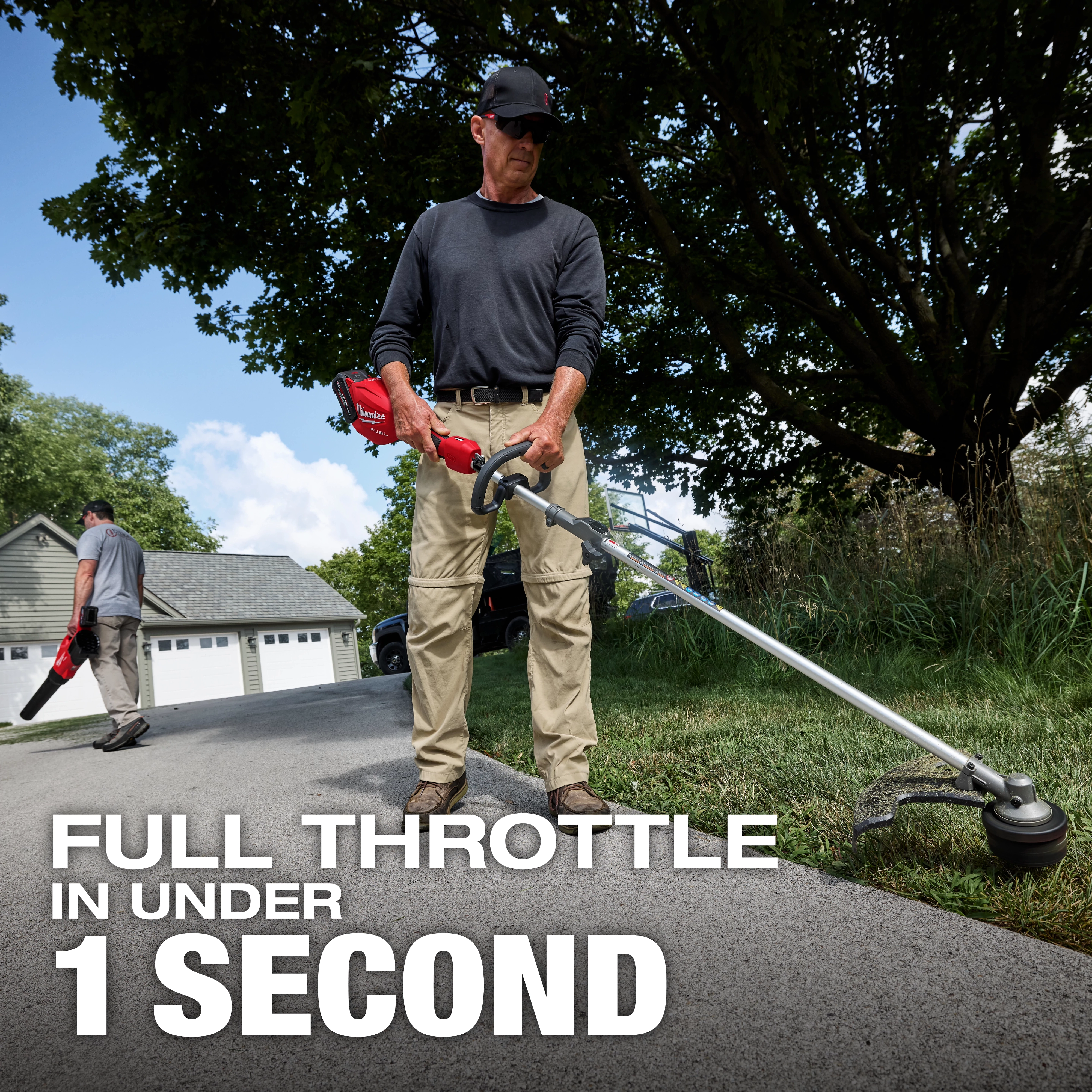 A person uses the M18 FUEL™ String Trimmer w/ QUIK-LOK™ Kit on a driveway, with bold text stating "FULL THROTTLE IN UNDER 1 SECOND" in the foreground, and another person using a blower in the background near a grey garage. Surrounding greenery and trees are visible.