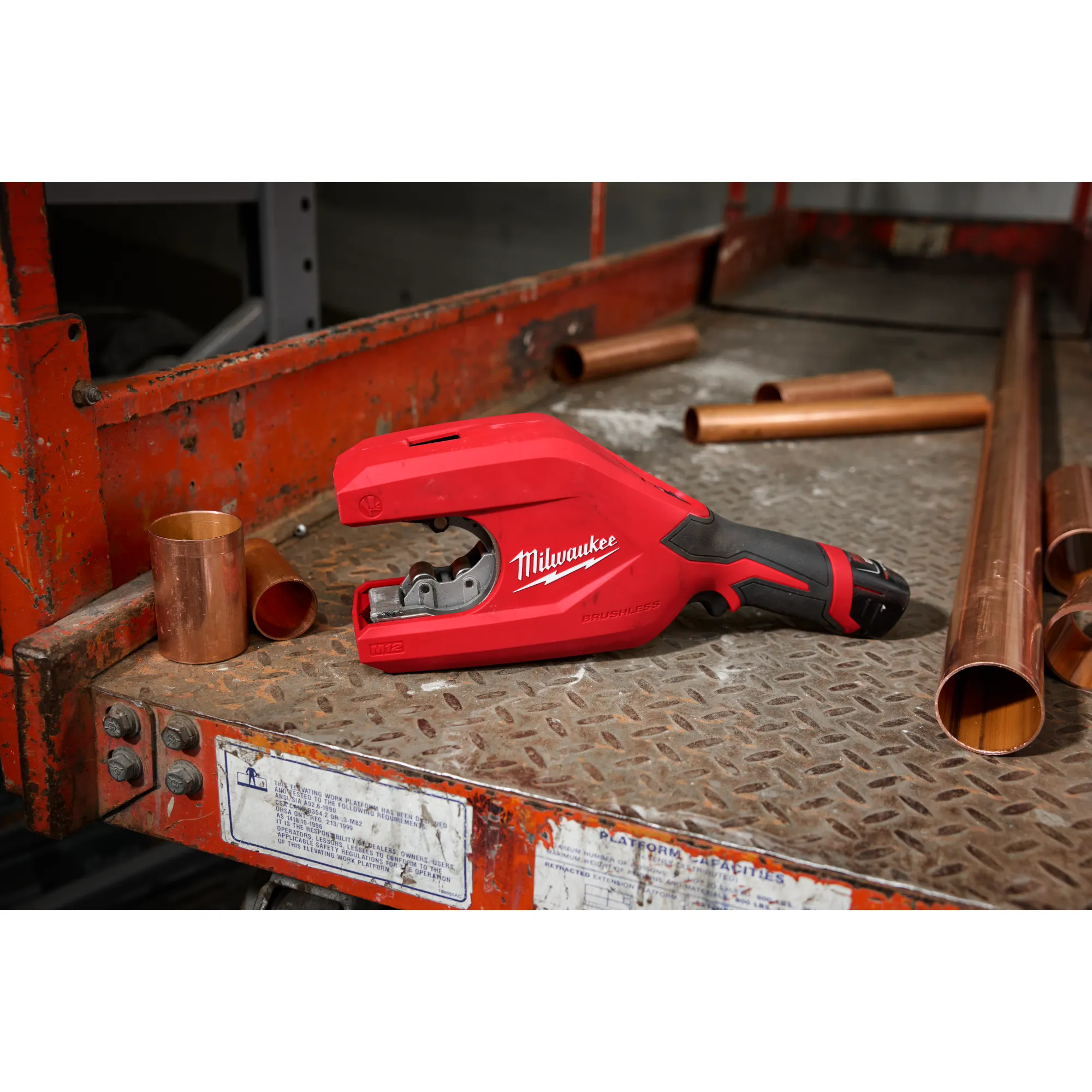 Image of the Milwaukee M12 Brushless 1-1/4" - 2" Copper Tubing Cutter sitting next to copper pipe on a jobsite