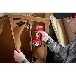 Worker using the Compact Brushless 1/4" Hex Impact Driver on a cabinet hinge