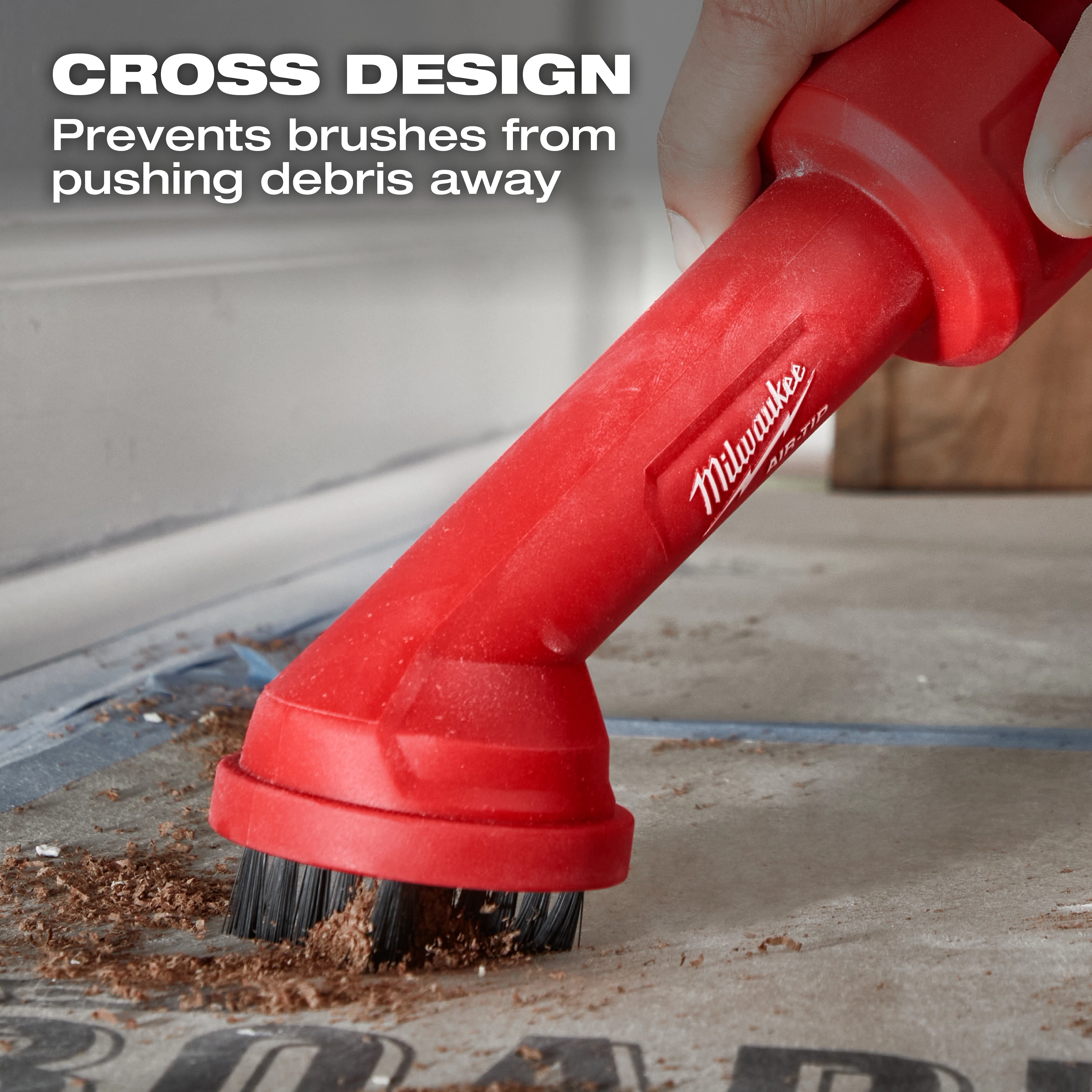 A close-up image of a red AIR-TIP™ Cross Brush Tool branded with "Milwaukee." It features a cross design, shown being used to brush away debris. The text reads, "Cross Design - Prevents brushes from pushing debris away."