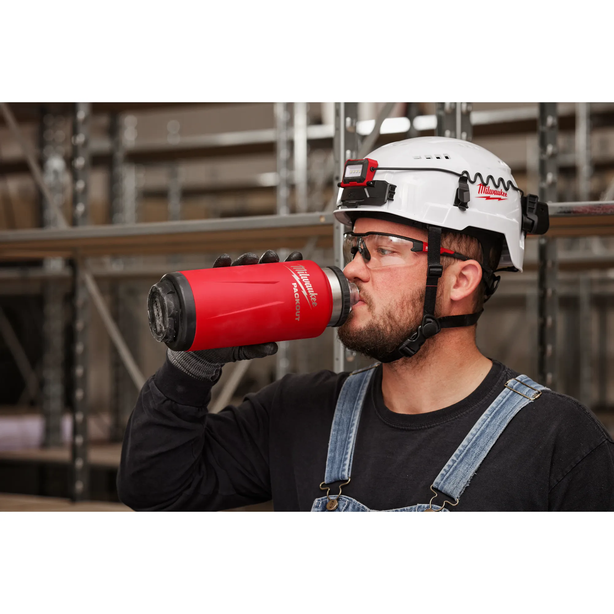 Image of a worker drinking from the Milwaukee PACKOUT Insulated Bottle in red